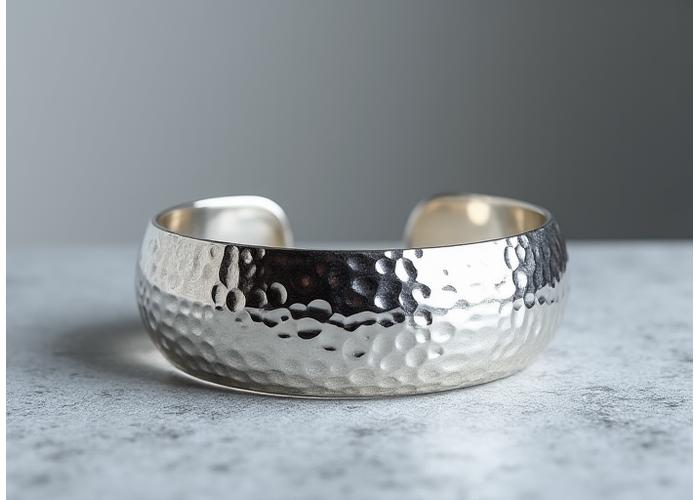 Un bracelet manchette en argent sterling avec une texture martelée et un design organique rappelant des vagues.